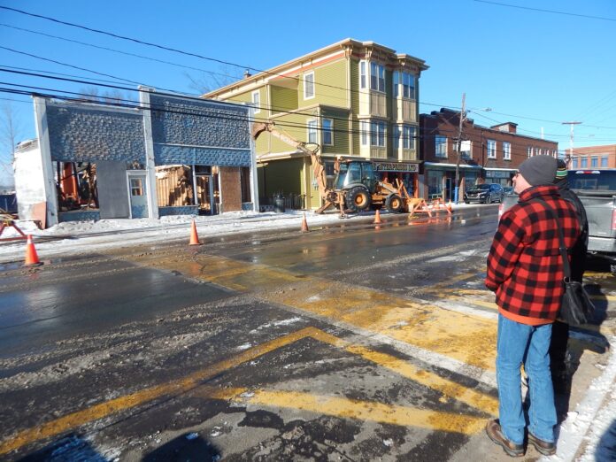 Eric Mosher and contractor Jeff Wood (A-1 Gutters) watch the demolition of the former Fowler barbershop on Water Street this morning.