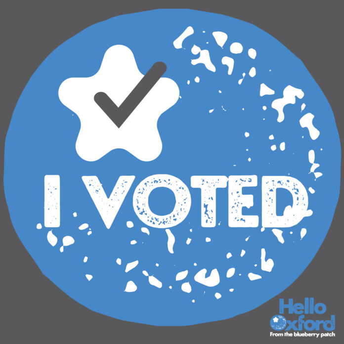 A stylized graphic of a blueberry with the text "I VOTED" and a checkmark. The "Hello Oxford" logo is in the bottom corner.