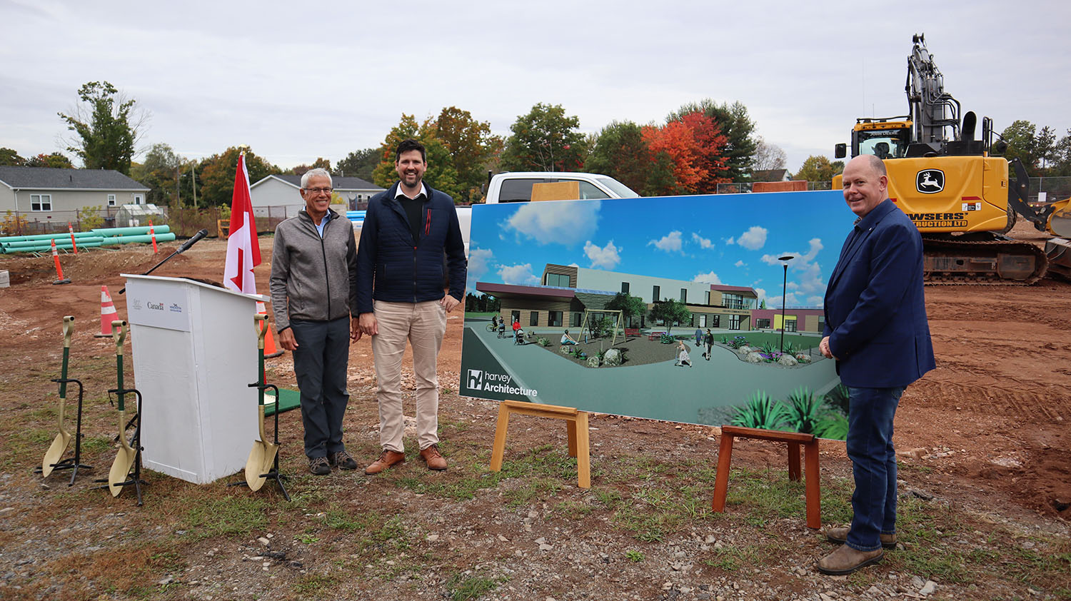 Oxford Community Centre Committee President David Hoffman; Federal Minister of Housing, Infrastructure & Communities Sean Fraser, and Nova Scotia Minister of Natural Resources and Renewables Tory Rushton, standing with a concept rendering of the new Oxford Community Centre
